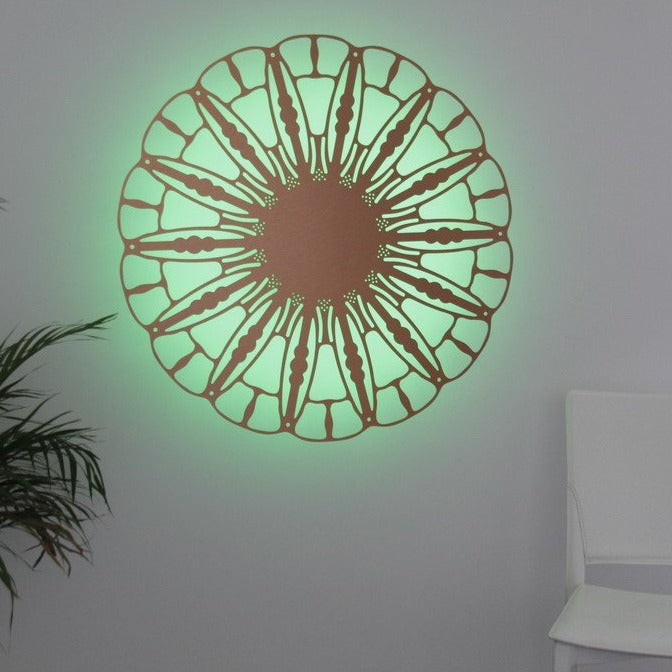KuvaLight Anemone wall lamp in brushed copper with green light, 80 cm version, shown in a warm home interior.