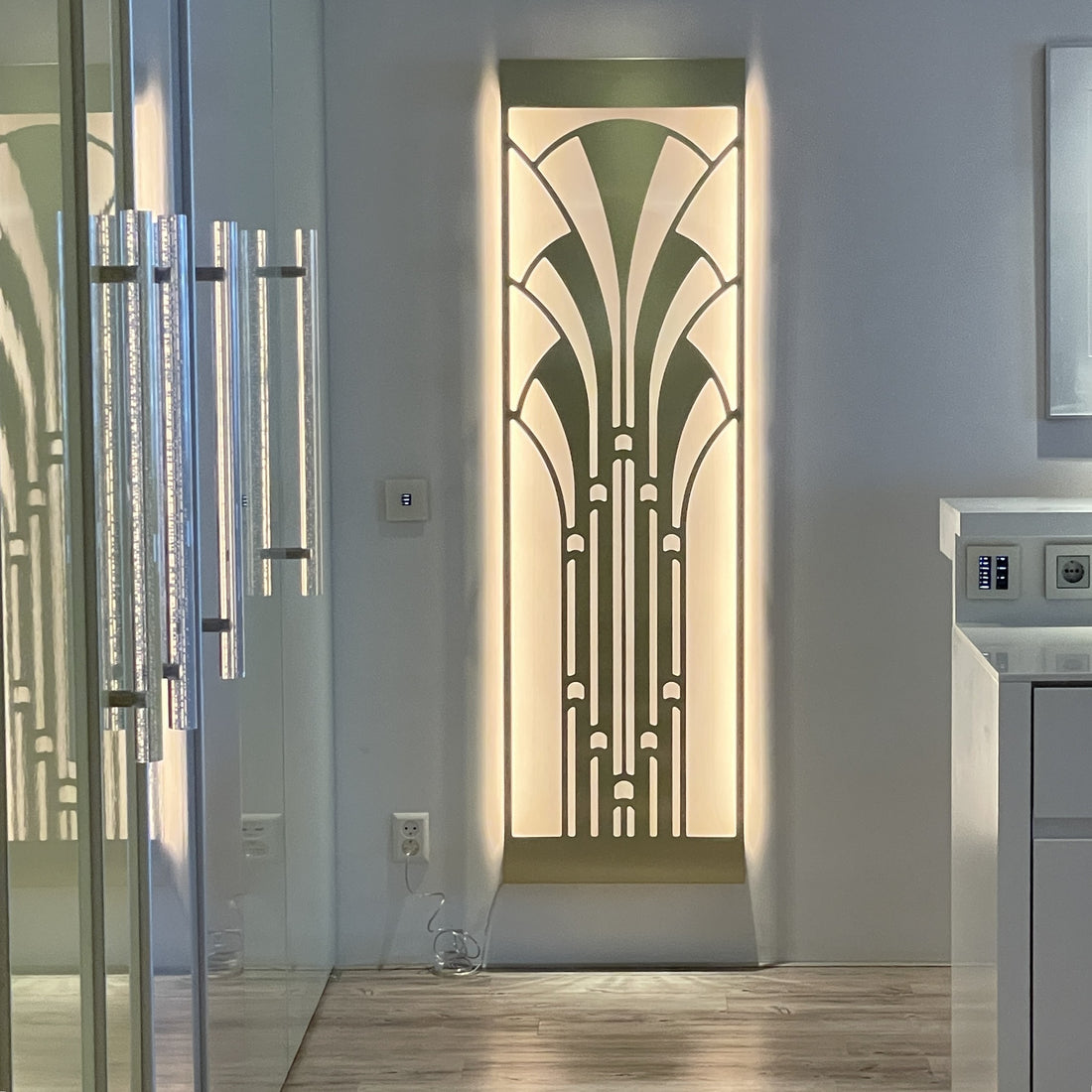 Art Deco Miami wall light in brushed gold with warm white illumination, installed vertically in a modern hallway.