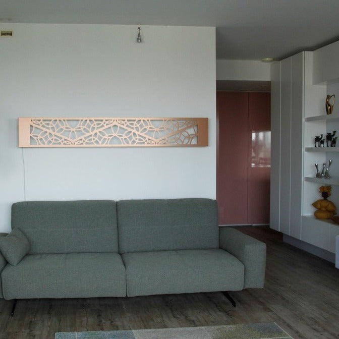 KuvaLight Minho 1 in brushed copper hanging horizontally above a sofa. The light of the KuvaLight is of and the light that comes from outside reflects beautifully on the brushed copper.