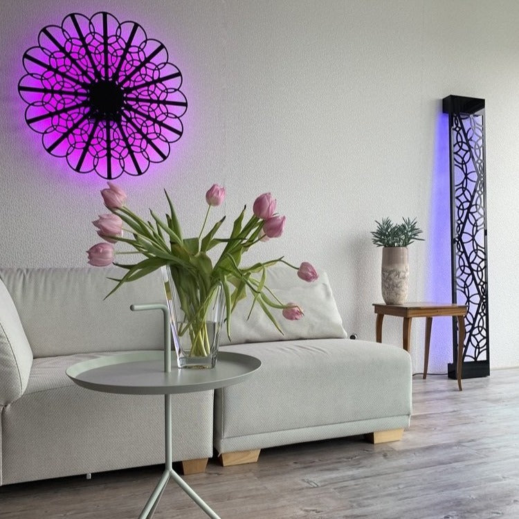 Combination of the KuvaLight Braga (80cm) and the KuvaLight MInho 1 both in Pianoa Black whereby for each light a different color light is chosen pink and blue/purple. The Minho 1 is leaning against the wall. Photographed in a home setting.