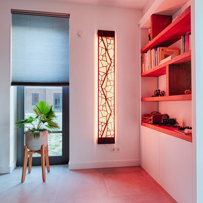 KuvaLight Mosaic in Piano Black with a yellow light in a home setting next to a custom mad bookcase..