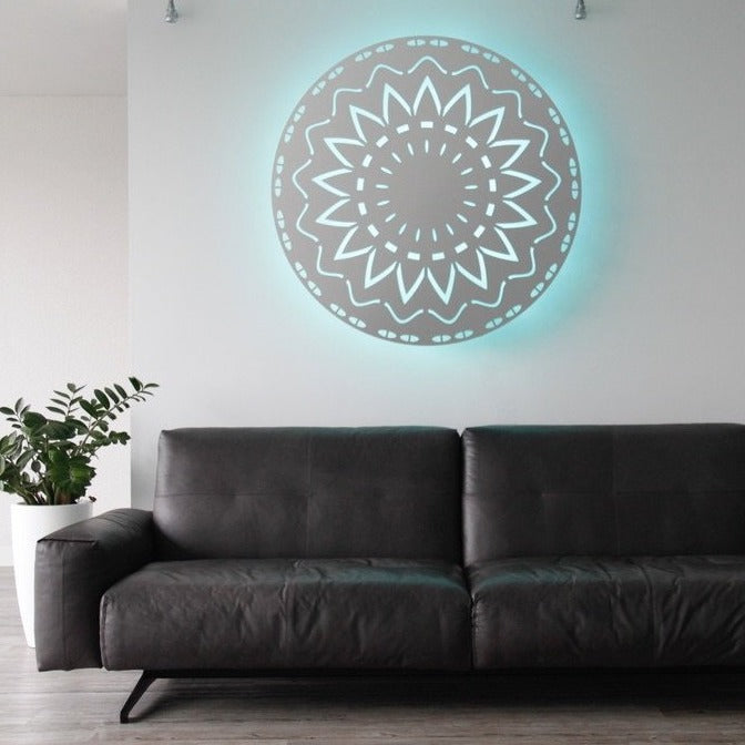 KuvaLight New Beginning (115cm) in brushed aluminum hanging above a sofa. The light color is a soft aqua blue which gives the room a nice cool atmosphere.