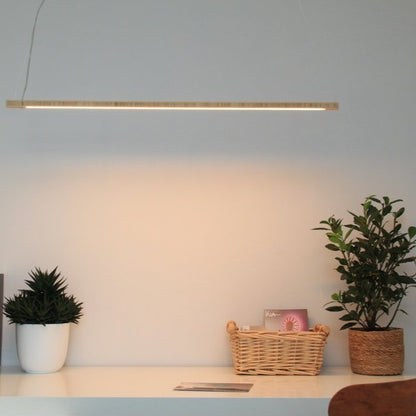 KuvaLight Line in Bamboo hanging above a desk. The color of the light can be adjusted from warm white to energizing cool white light and is also dimmable.