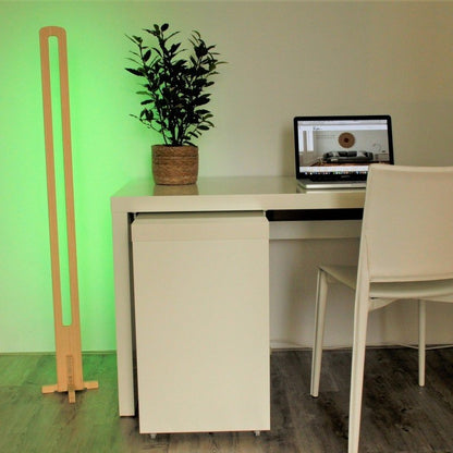 KuvaLight Parallel in Bamboo with a green relaxing light standing next to a desk.